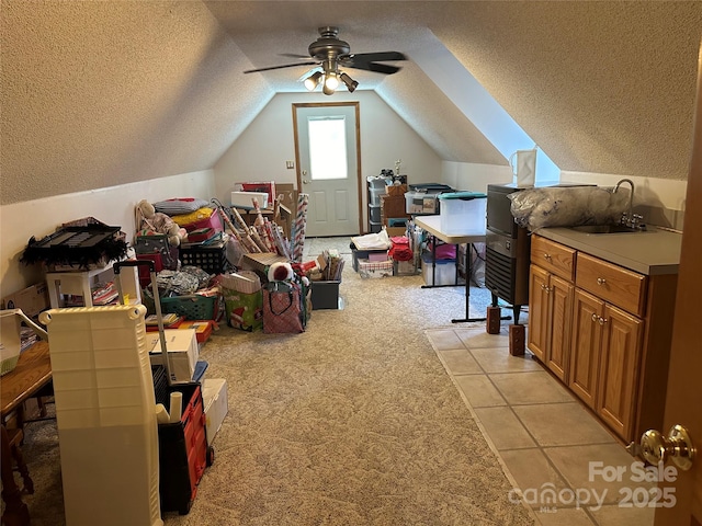 rec room featuring a textured ceiling, lofted ceiling, ceiling fan, light carpet, and sink