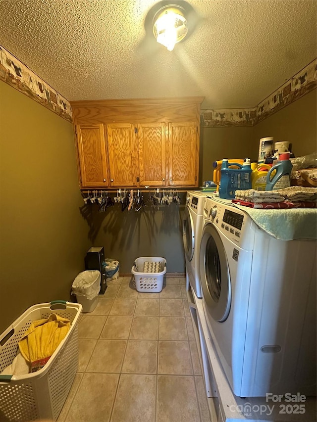 washroom featuring washer and dryer, cabinets, light tile patterned flooring, and a textured ceiling