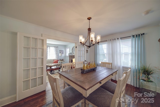 dining area featuring a notable chandelier, dark wood-type flooring, and a brick fireplace