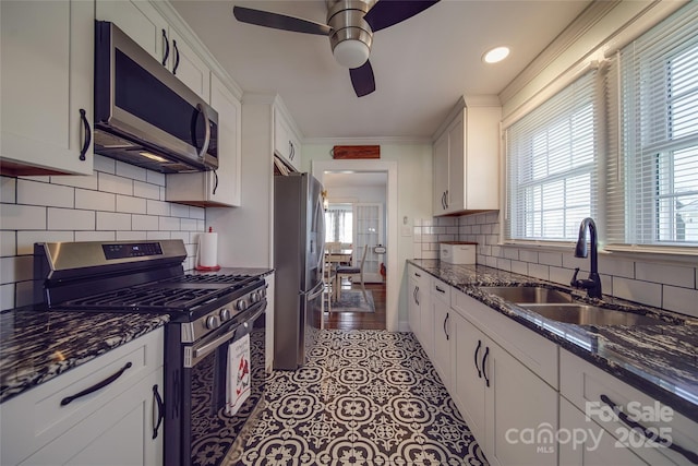 kitchen with sink, white cabinetry, stainless steel appliances, and dark stone counters