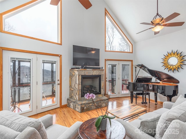 living room with hardwood / wood-style floors, high vaulted ceiling, french doors, ceiling fan, and a fireplace