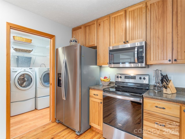 1185 Mule Stomp Rd, Clyde, NC 28721 - kitchen featuring appliances with stainless steel finishes, washer and dryer, light wood-style flooring, dark countertops, and a textured ceiling