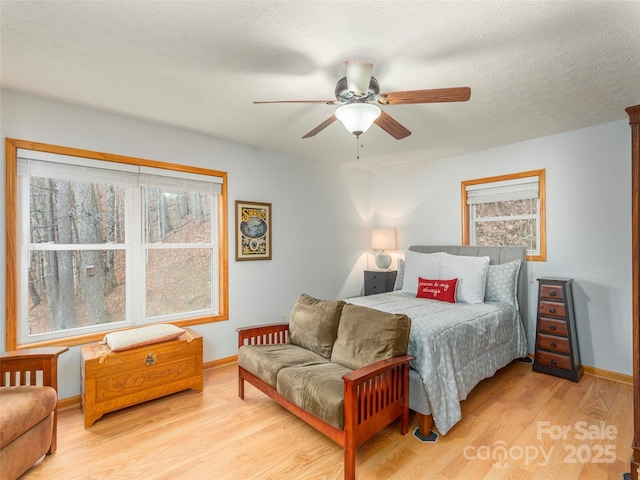 bedroom with multiple windows, a textured ceiling, light hardwood / wood-style floors, and ceiling fan