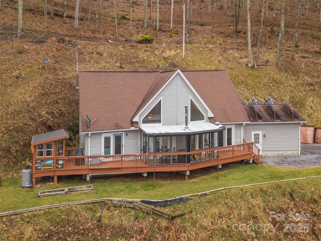 rear view of house featuring a sunroom, a yard, and a deck