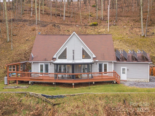 rear view of property with a yard, a deck, and a sunroom