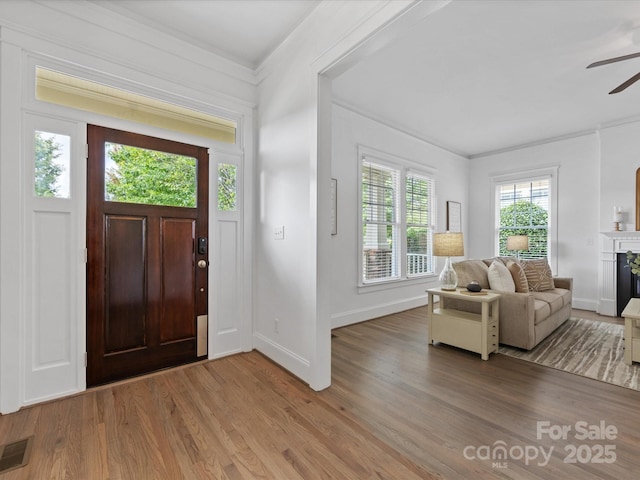 entryway featuring light hardwood / wood-style flooring, ceiling fan, ornamental molding, and a premium fireplace