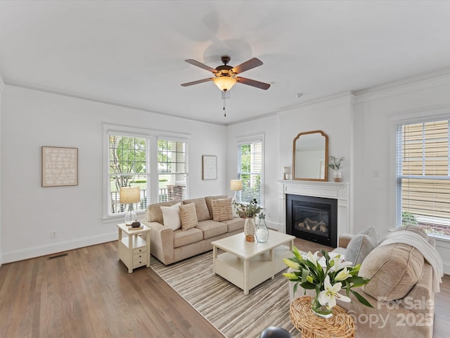 living room featuring light wood-type flooring, ceiling fan, and ornamental molding