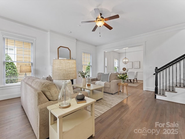 living room featuring wood-type flooring, ceiling fan with notable chandelier, a wealth of natural light, and ornamental molding