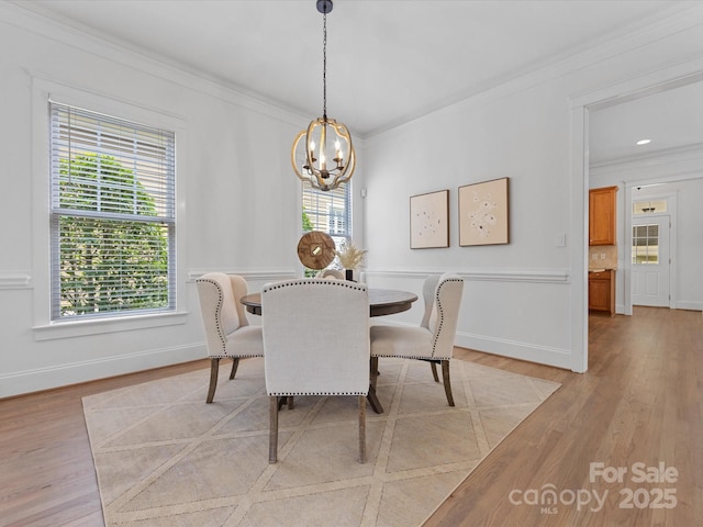 dining area featuring light wood-type flooring, a wealth of natural light, and ornamental molding