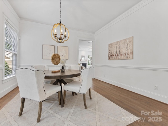 dining area with a healthy amount of sunlight, light hardwood / wood-style flooring, ornamental molding, and a notable chandelier