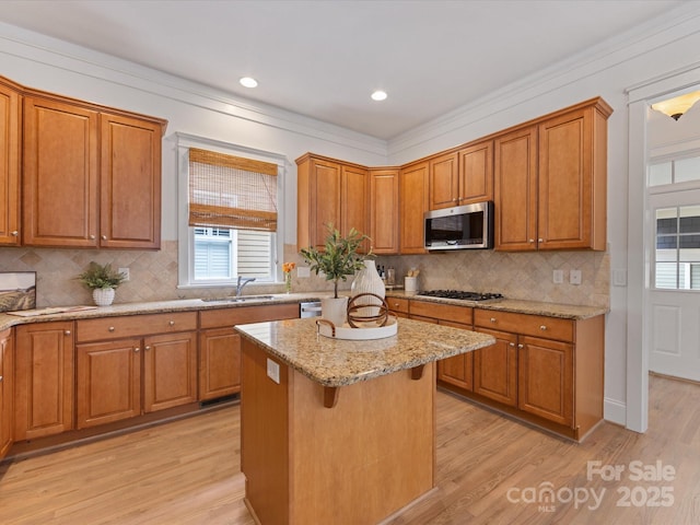 kitchen featuring sink, stainless steel appliances, light stone counters, a breakfast bar, and a kitchen island