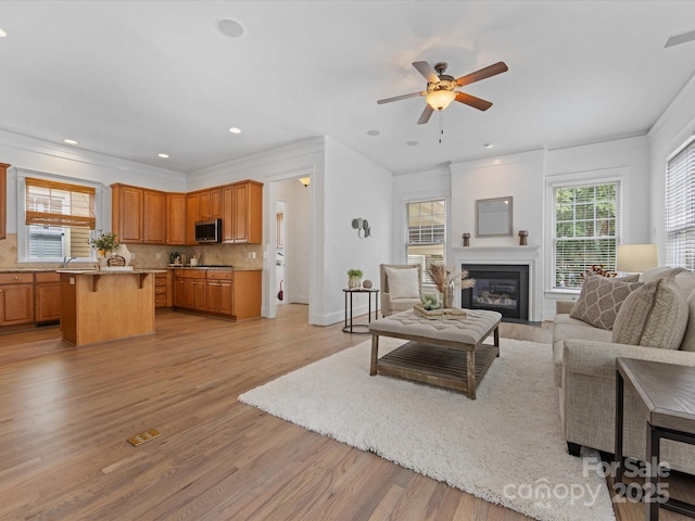 living room featuring ceiling fan, light hardwood / wood-style floors, and ornamental molding