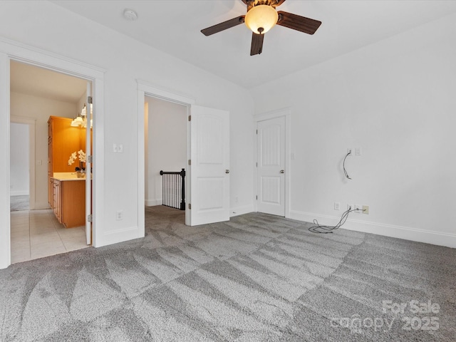 unfurnished bedroom with connected bathroom, light colored carpet, and ceiling fan