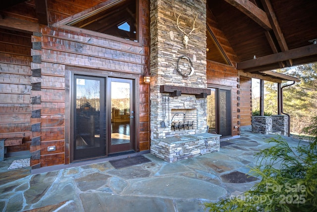 view of exterior entry featuring a patio and an outdoor stone fireplace