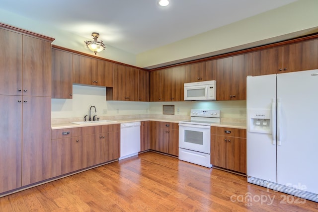 kitchen featuring sink, white appliances, and light hardwood / wood-style flooring