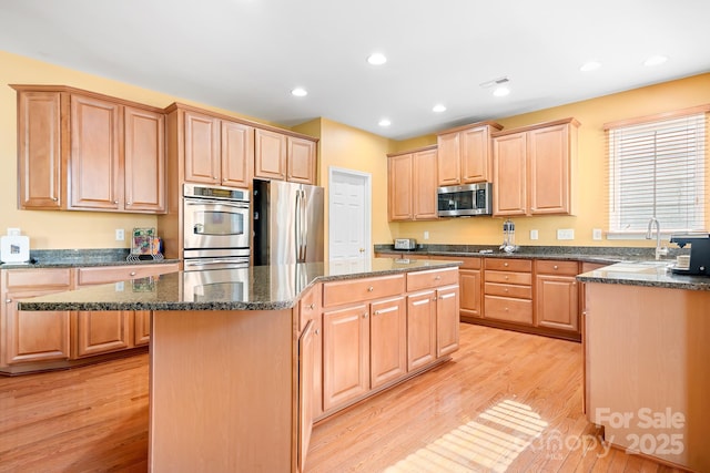 kitchen featuring sink, light hardwood / wood-style floors, light brown cabinetry, appliances with stainless steel finishes, and a kitchen island