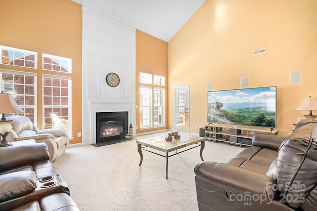 carpeted living room with a large fireplace and high vaulted ceiling