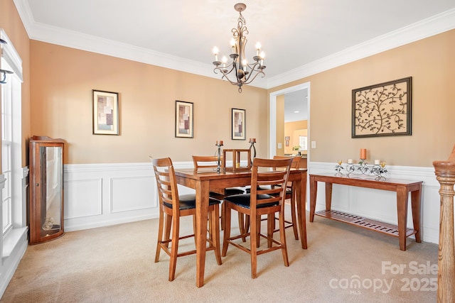 carpeted dining space featuring a chandelier and ornamental molding