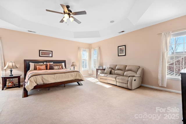 bedroom featuring a raised ceiling, ceiling fan, and light carpet