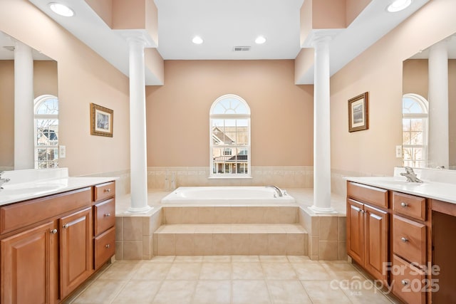 bathroom with tile patterned flooring, vanity, a relaxing tiled tub, and a healthy amount of sunlight