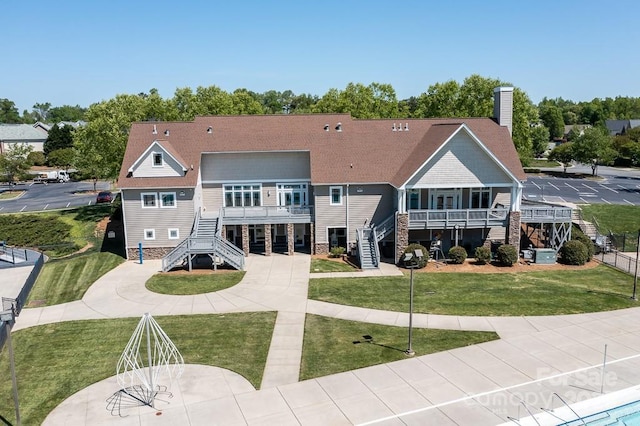 rear view of property featuring a balcony and a lawn