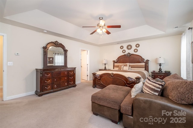 carpeted bedroom featuring a tray ceiling and ceiling fan