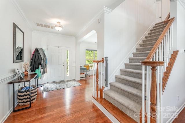 entryway with wood-type flooring and crown molding