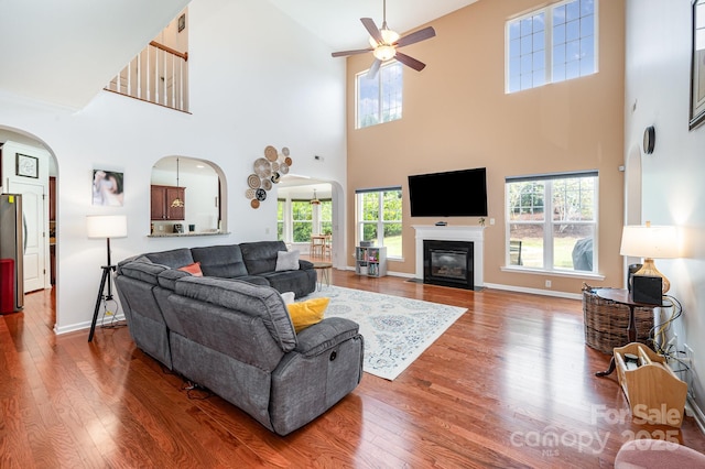 living room featuring ceiling fan, a towering ceiling, and hardwood / wood-style flooring