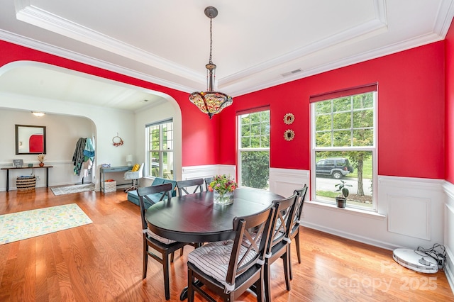 dining area with a tray ceiling, crown molding, and light hardwood / wood-style floors