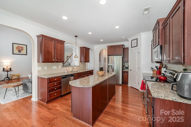 kitchen featuring light stone countertops, hanging light fixtures, stainless steel appliances, backsplash, and a kitchen island