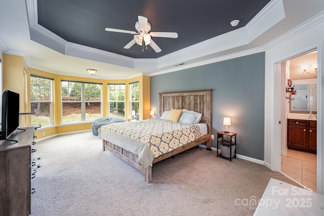 carpeted bedroom featuring ceiling fan, a raised ceiling, crown molding, and connected bathroom