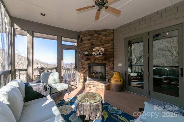 living room with a stone fireplace, ceiling fan, and hardwood / wood-style flooring