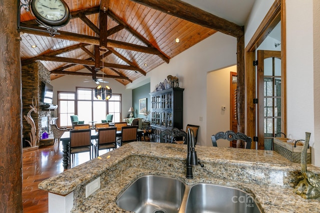 kitchen with sink, wood ceiling, beam ceiling, high vaulted ceiling, and light stone countertops