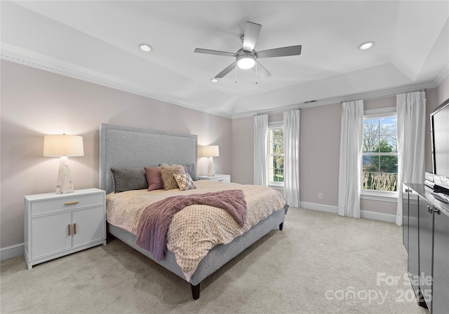 bedroom featuring ceiling fan, light colored carpet, multiple windows, and a tray ceiling