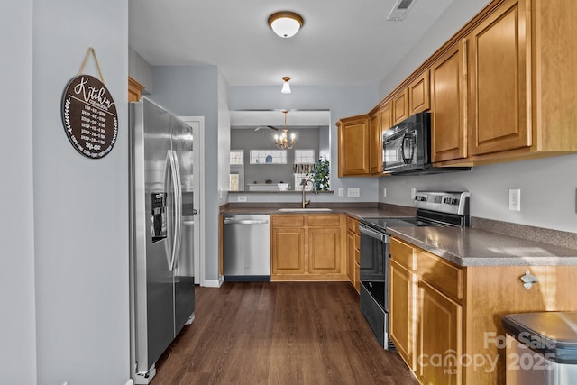 kitchen featuring appliances with stainless steel finishes, dark hardwood / wood-style flooring, sink, decorative light fixtures, and a notable chandelier