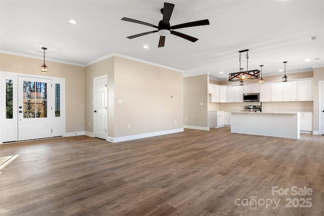 unfurnished living room featuring ceiling fan, wood-type flooring, and ornamental molding