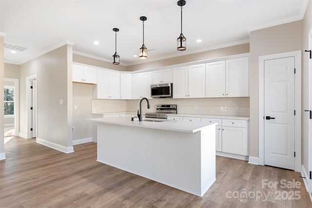 kitchen featuring hanging light fixtures, light wood-type flooring, an island with sink, white cabinetry, and stainless steel appliances