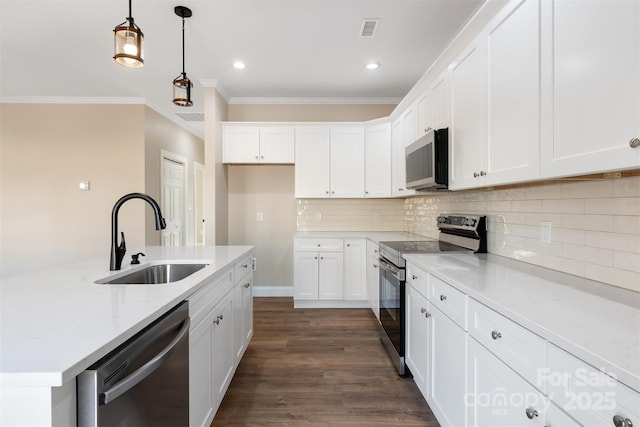 kitchen with light stone countertops, appliances with stainless steel finishes, sink, decorative light fixtures, and white cabinetry