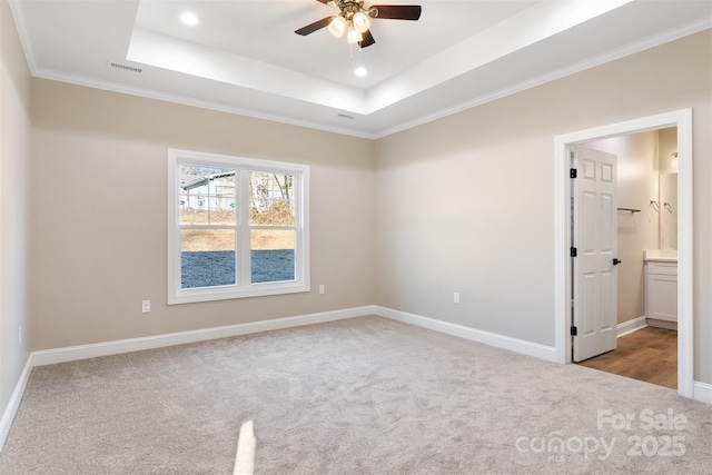 empty room with ceiling fan, crown molding, light carpet, and a tray ceiling