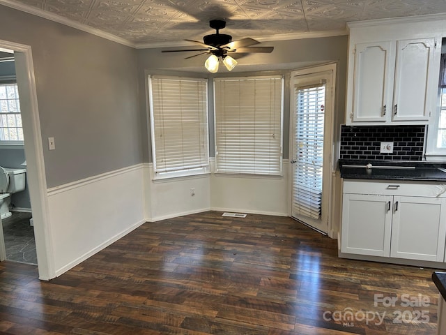 unfurnished dining area with ceiling fan, dark hardwood / wood-style floors, ornamental molding, and a wealth of natural light