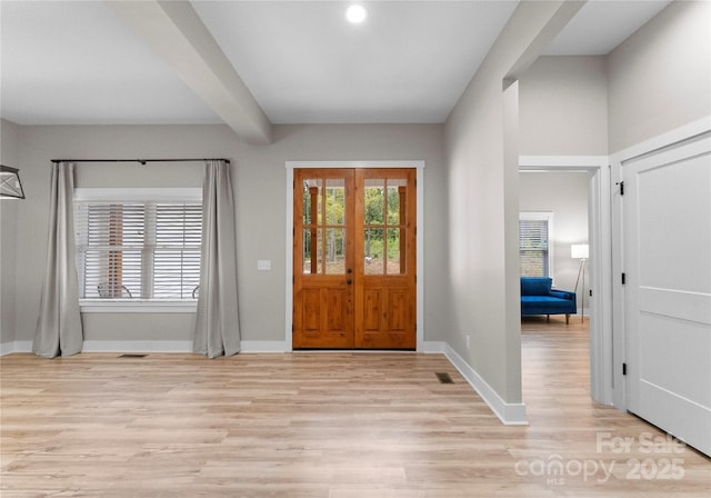 foyer entrance with french doors, beamed ceiling, and light hardwood / wood-style flooring