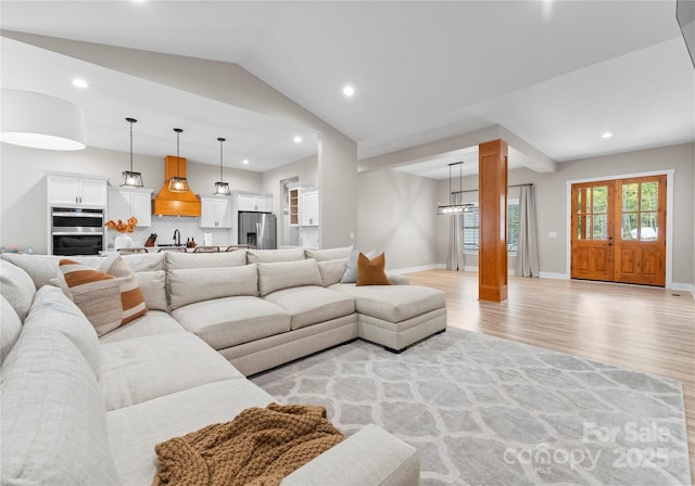 living room with light hardwood / wood-style floors, lofted ceiling, and sink