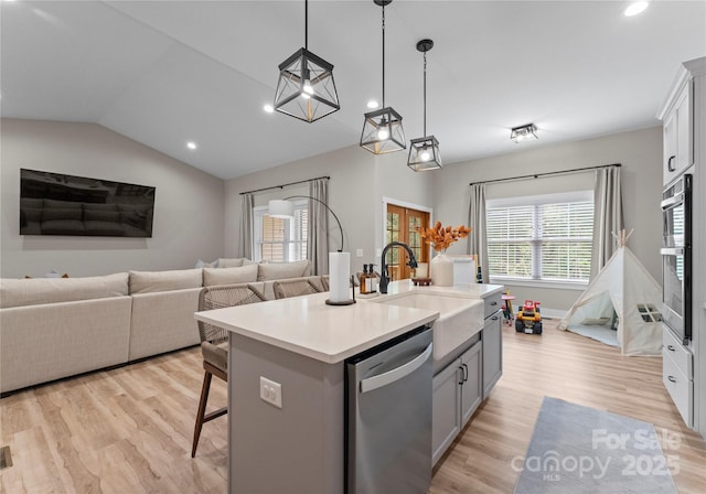 kitchen featuring a breakfast bar, stainless steel appliances, a kitchen island with sink, sink, and decorative light fixtures