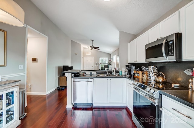 kitchen featuring kitchen peninsula, white cabinetry, vaulted ceiling, and appliances with stainless steel finishes