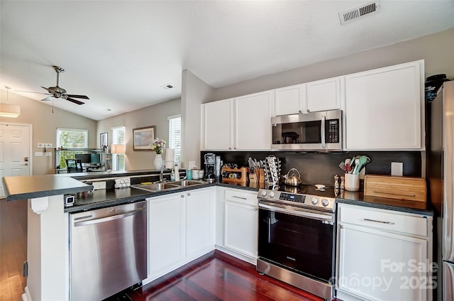 kitchen with kitchen peninsula, stainless steel appliances, white cabinets, and lofted ceiling