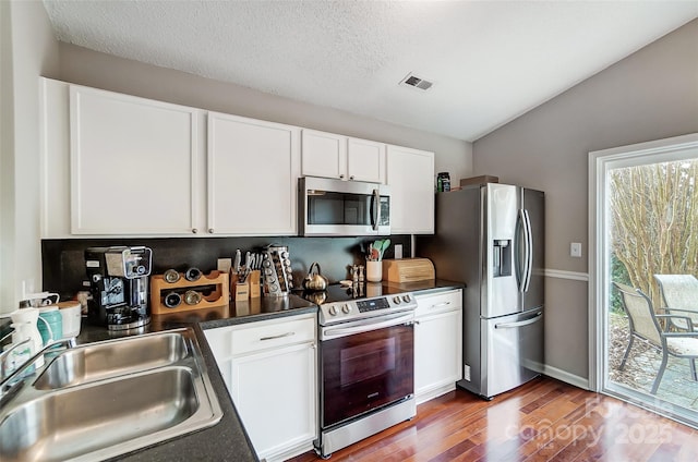 kitchen with white cabinets, appliances with stainless steel finishes, lofted ceiling, and sink