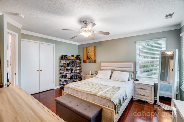 bedroom with dark wood-type flooring, ceiling fan, ornamental molding, a textured ceiling, and a closet