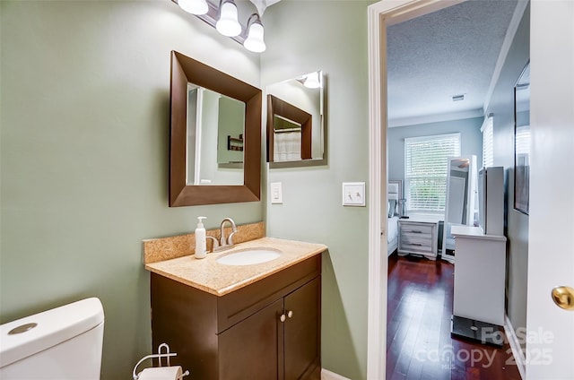 bathroom with a textured ceiling, vanity, toilet, and wood-type flooring