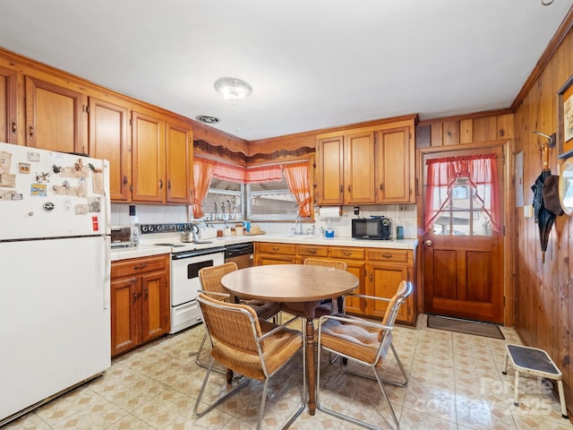 kitchen featuring wood walls, decorative backsplash, light tile patterned flooring, and white appliances