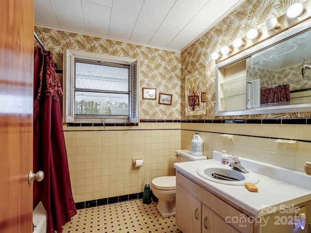 full bathroom featuring shower / bathtub combination with curtain, toilet, vanity, tile walls, and ornamental molding